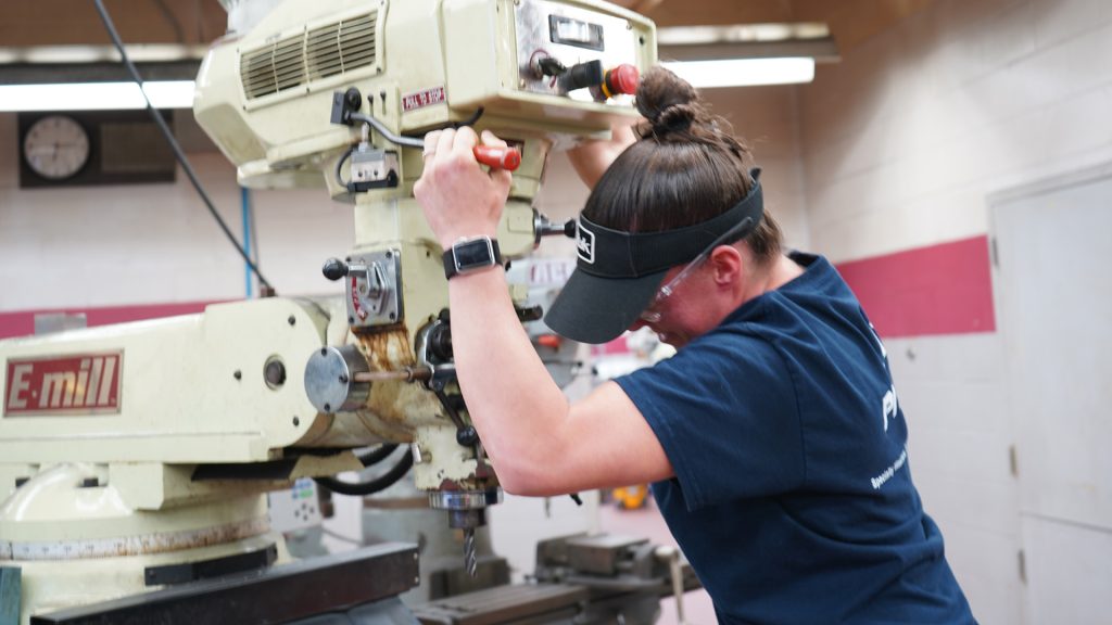 Female Student working on drill press in lab